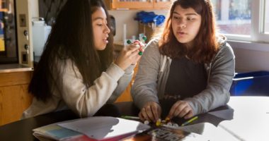 Two female students in a high school chemistry classroom working on a 3-D model