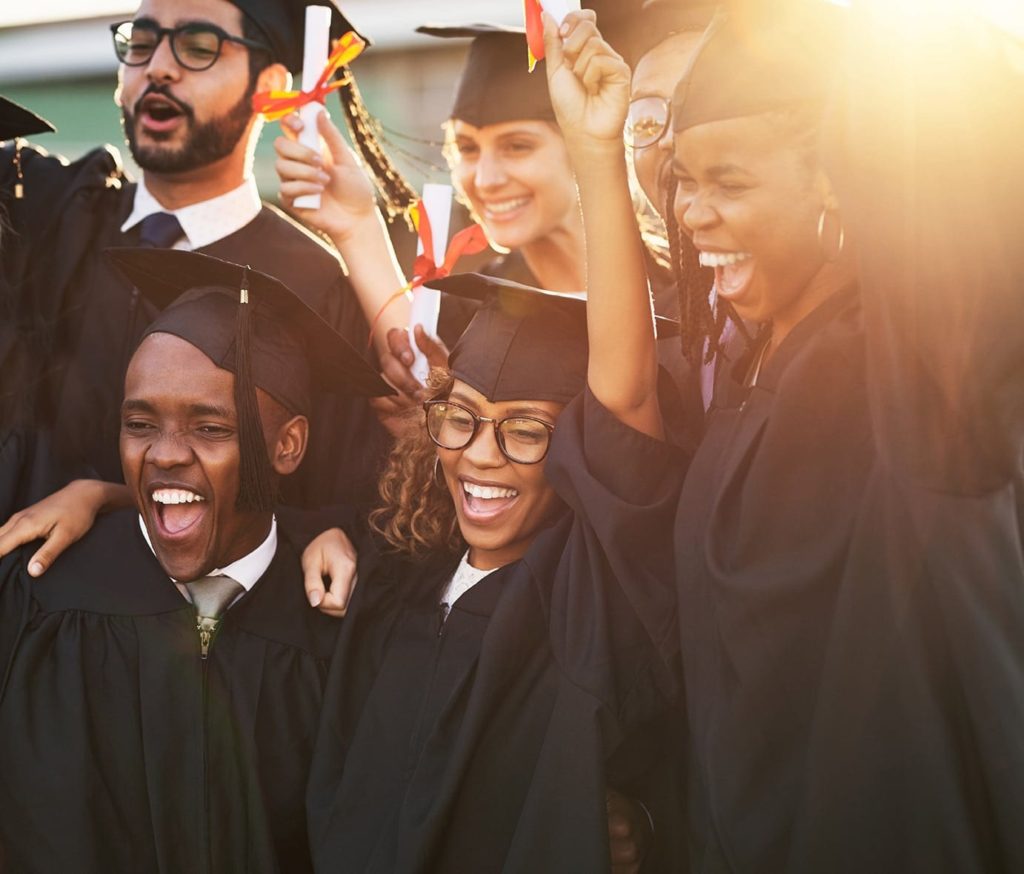 Group of diverse college students wearing gap and gowns celebrating graduation