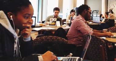 Diverse students of color working on laptops in a school setting