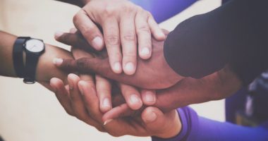 A diverse group of people joins hands