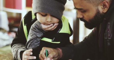 A man and a toddler drawing on paper