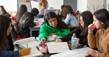 A group of students work together to solve problems in their textbook during class