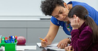 Female elementary teacher with female student in dual-language class